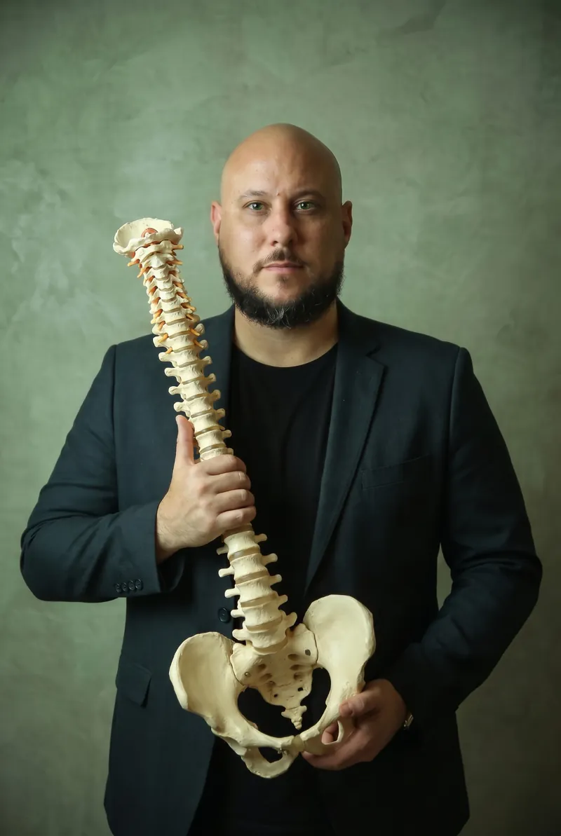 Dr. Aléssio Novais, fisioterapeuta, segurando um modelo de coluna vertebral