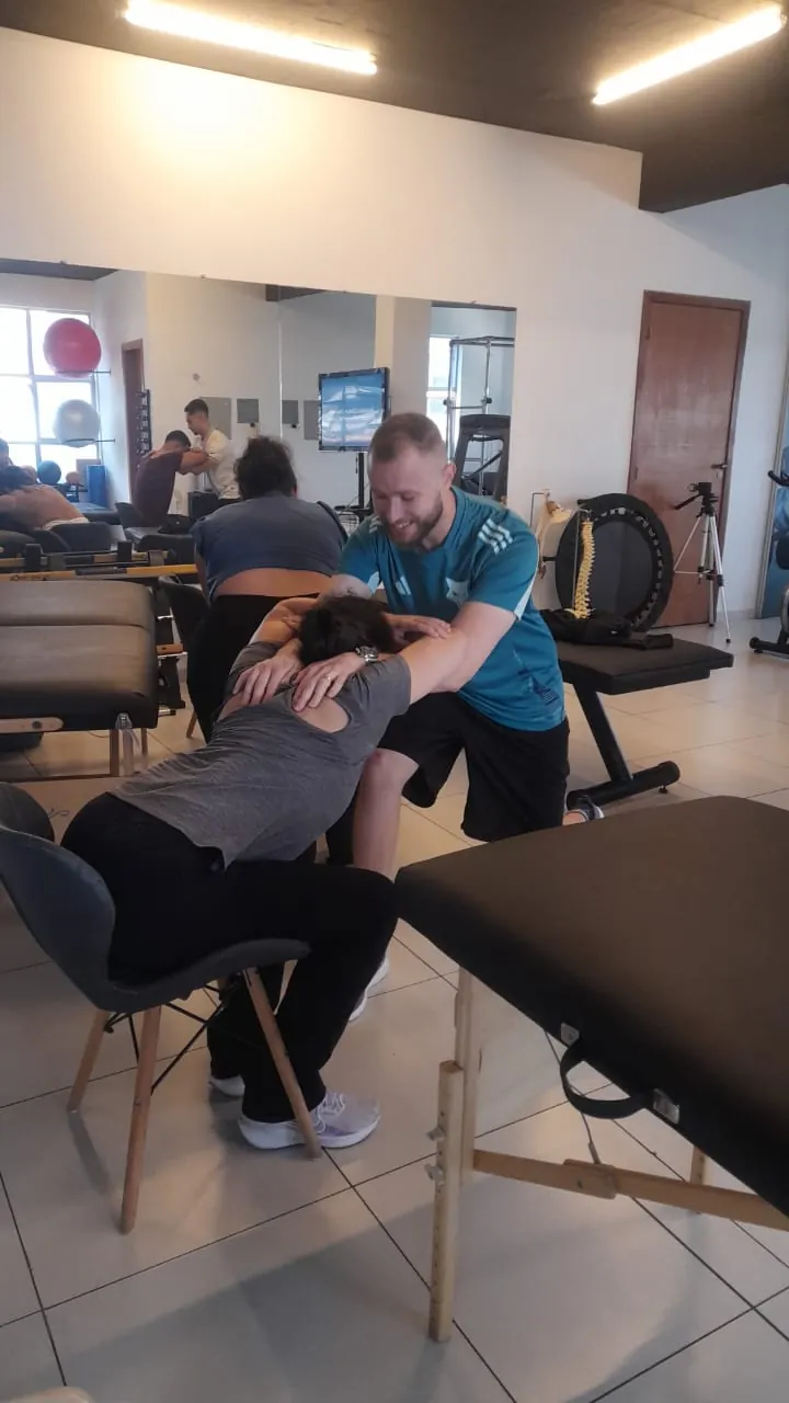 Fisioterapeuta aplicando técnica manual supervisionada em paciente sentada durante o treinamento