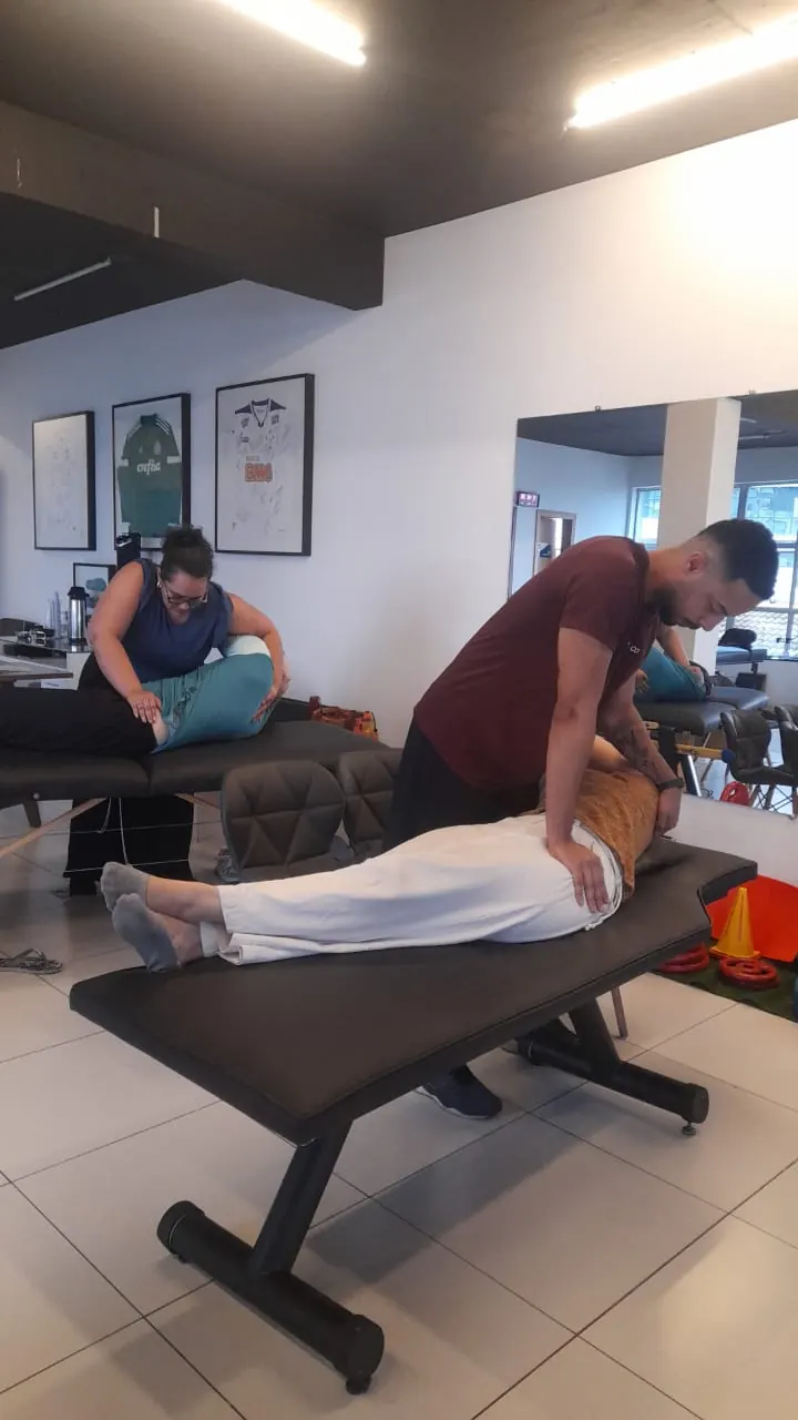 Duplas de fisioterapeutas praticando técnicas em macas durante o encontro presencial